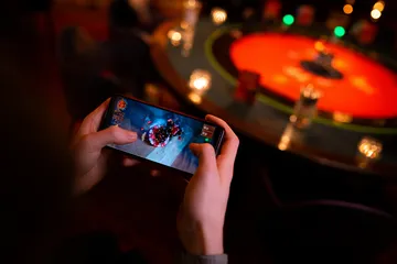 A player using their smartphone during a festive local event, representing SLO16’s fully mobile-friendly casino.